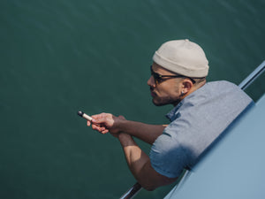 Man in a yacht holding a gold RELX Infinity device and gazing at the distance