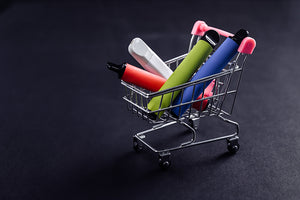 Vape pens lie in a mini shopping cart.