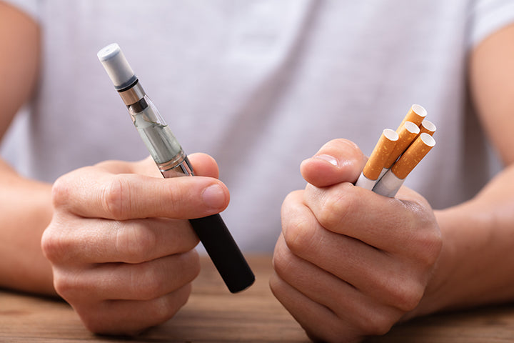 man holding vape device and cigarettes in hands